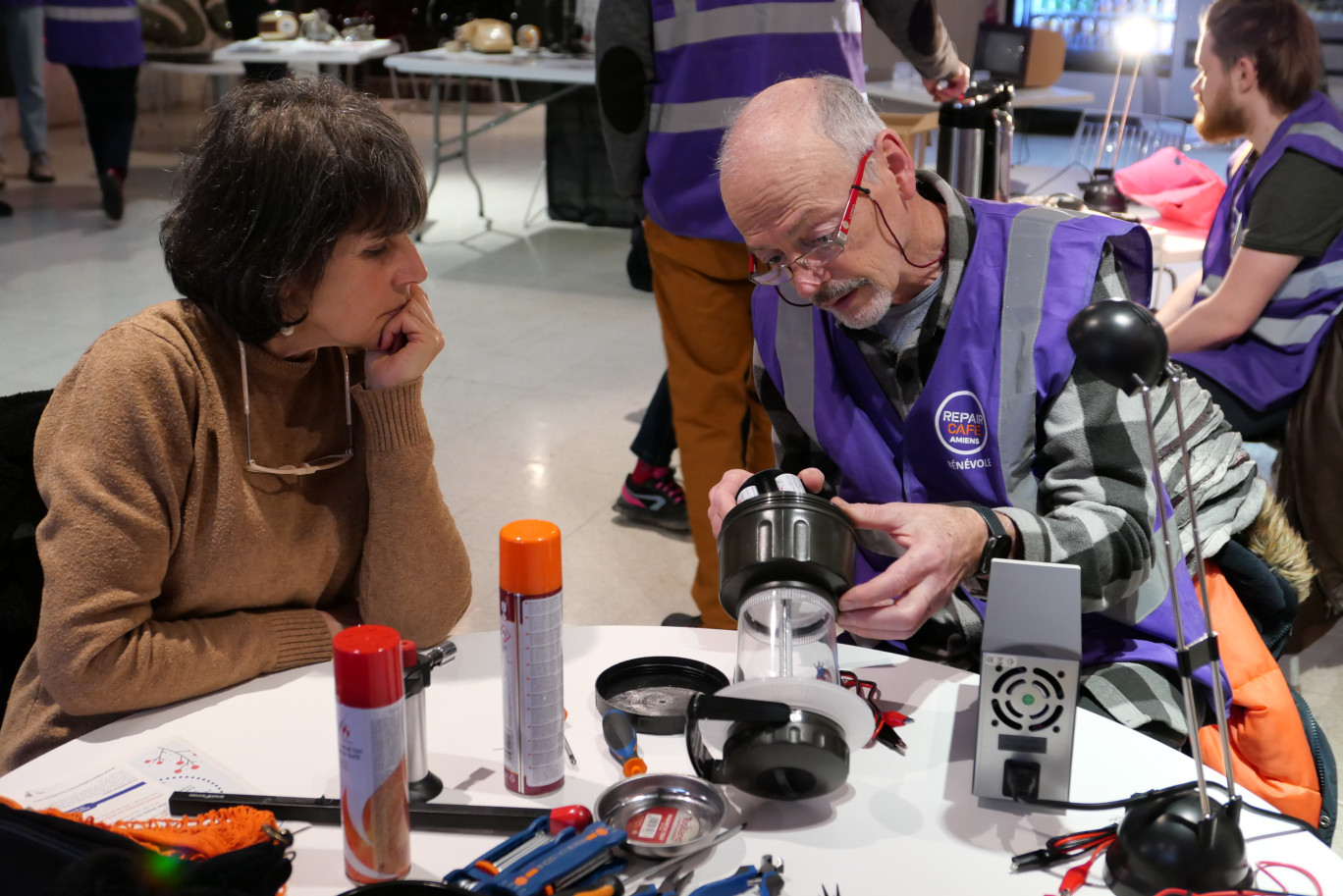 Marion est venue pour la deuxième fois au Repair café, et Pierre, bénévole, lui montre comment réparer sa lampe de camping. ©Aletheia Press/ E.Castel