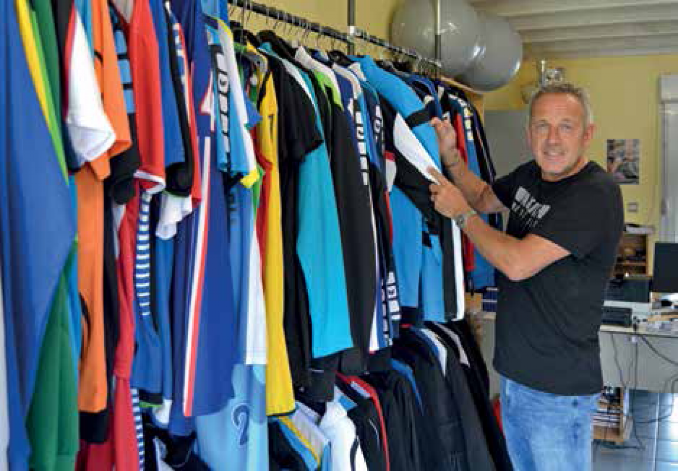 Patrick Devisme devant ses t-shirts et polos en exposition dans son showroom.